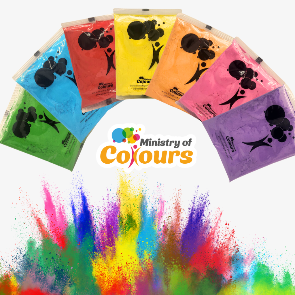 A collection of packaged colour throwing powders from the Ministry of Colours, displayed in a fan-like arrangement with colours ranging from red, yellow, pink, green, blue, and purple, with a splash of paint at the bottom representing the product in use.